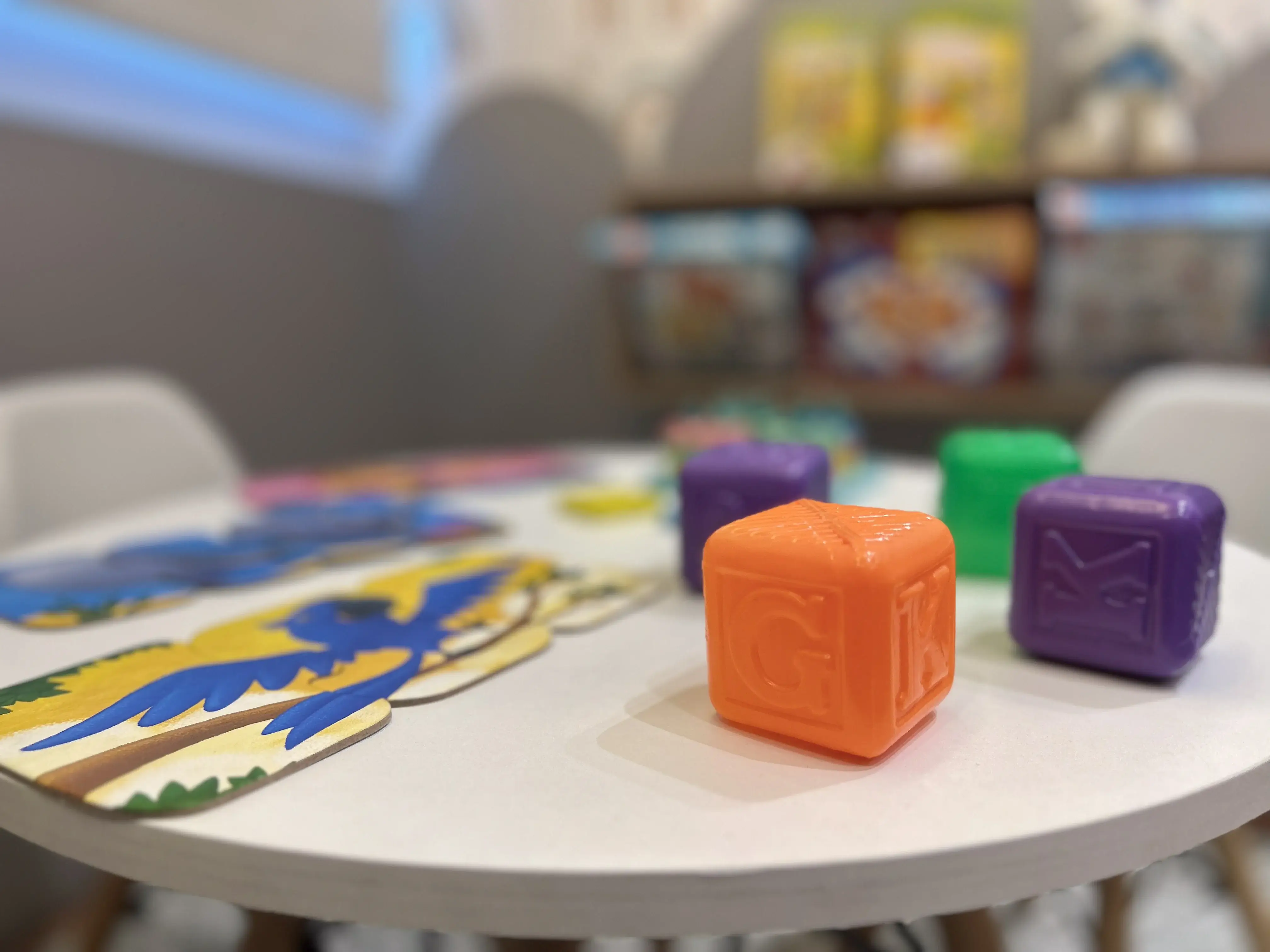 Cubos coloridos com letras e brinquedos terapêuticos sobre mesa infantil do consultório